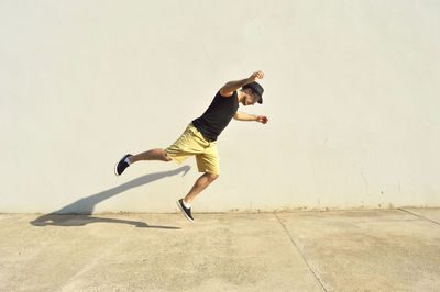 Full length of man jumping by wall