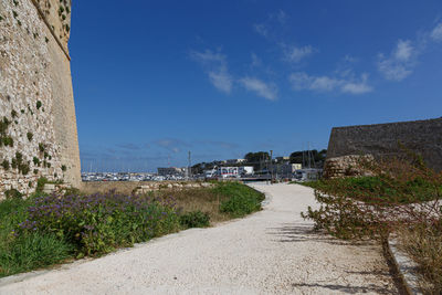 Road by buildings against blue sky