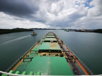 Vessel navigating over sea against cloudy sky