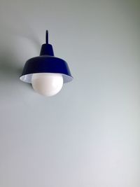 Low angle view of illuminated light bulb against wall