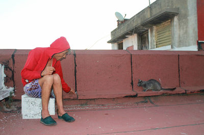 Woman sitting on retaining wall in city