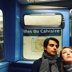 Full length of young couple sitting at subway station