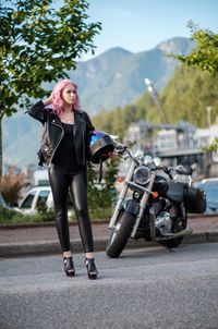 Full length of woman with helmet on road towards motorcycle.