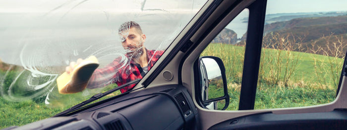 Man cleaning camper van windshield outdoor