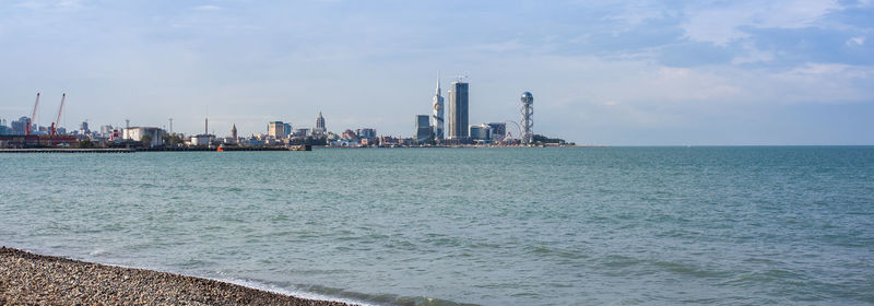 Scenic view of sea by buildings against sky