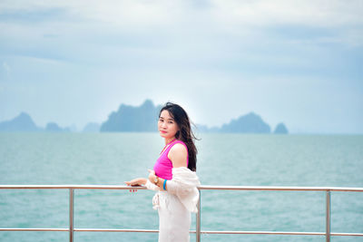 Portrait of young woman standing against sea