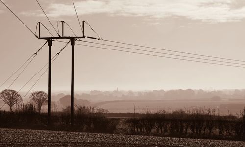Electricity pylon on field against sky