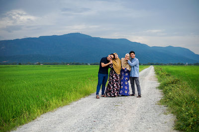 Rear view of friends on field against sky