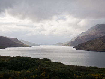 Scenic view of sea and mountains against cloudy sky