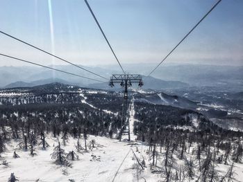 Ski lift over snow covered land against sky