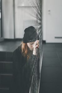 Close-up of young woman standing against wall