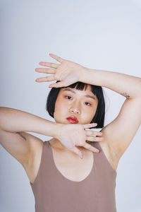 Portrait of young woman gesturing against white background