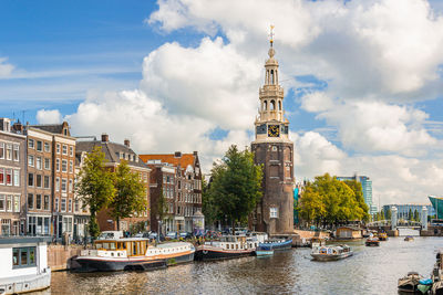 Buildings at waterfront against cloudy sky