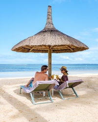 Happy couple sitting on lounge chair at beach
