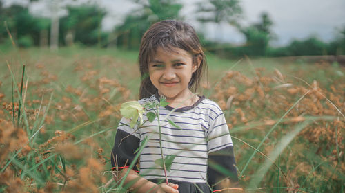 Portrait of smiling girl standing on field