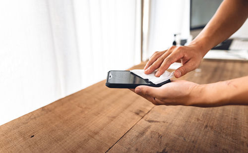 Midsection of man using mobile phone on table