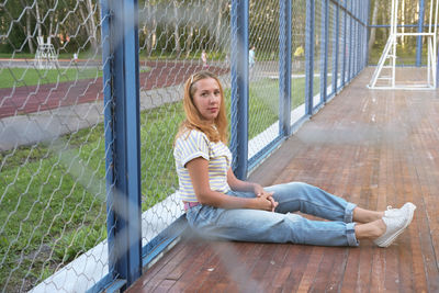 Woman relaxing on basketball playground. outdoor woman sitting and looking at camera