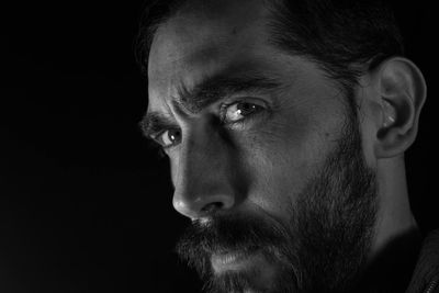 Close-up portrait of young man against black background