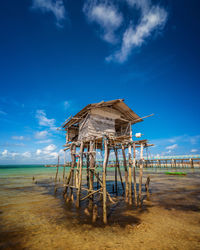 Lifeguard hut on beach against blue sky