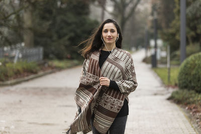 Portrait of young woman listening music while standing on road