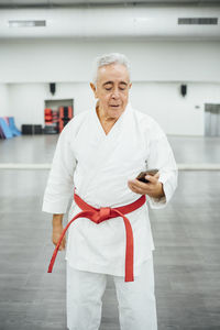 Senior karate master using mobile cell phone