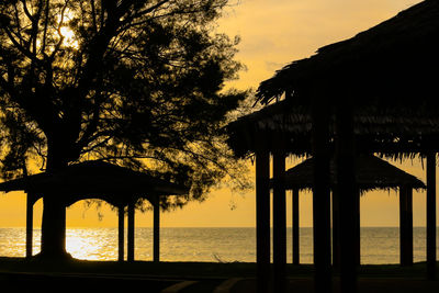 Silhouette trees by sea against sky during sunset