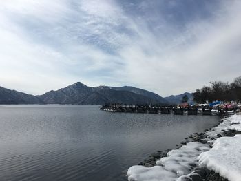 Scenic view of lake by snowcapped mountains against sky