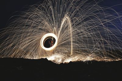 Man spinning wire wool on field at night