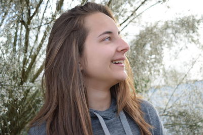 Portrait of smiling young woman against trees