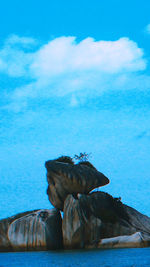 Rock formation by sea against blue sky