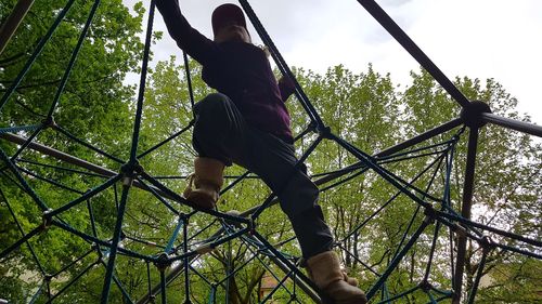 Low angle view of girl playing at jungle gym in playground