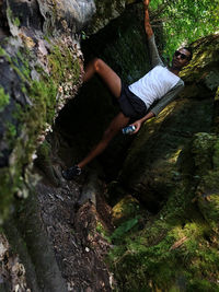 Midsection of man on rock in forest