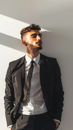 Portrait of young man standing against wall