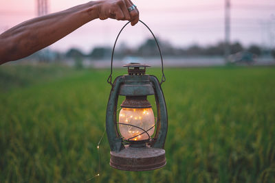 Close-up of hand holding illuminated electric lamp on field