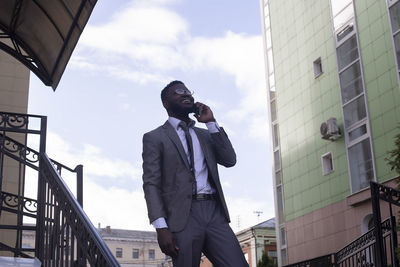 Low angle view of man standing by buildings against sky