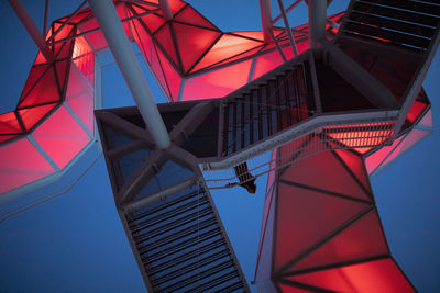 Low angle view of woman standing on illuminated elevated walkway at dusk