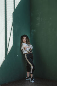 Portrait of a young woman standing against wall