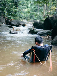 Rear view of woman sitting in lake