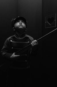 Boy wearing uniform while holding gun at home