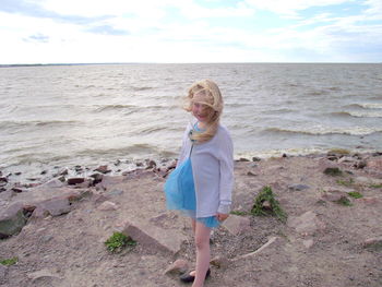 Portrait of smiling girl standing on beach against sky