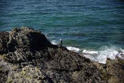 High angle view of man standing on rock in sea