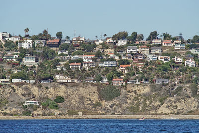 Aerial view of townscape by sea against clear sky