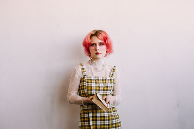 Young stylish woman standing vintage studio, bright make up and colored hair, looking at camera