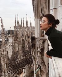 Young woman with arms outstretched against buildings in city