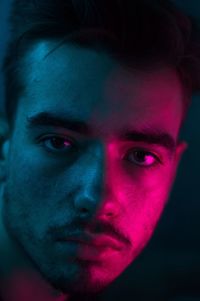 Pink light falling on young man in darkroom