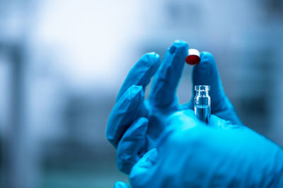 Close-up of hand holding bottle against blurred background