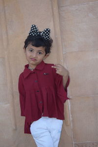 Portrait of girl standing against red wall