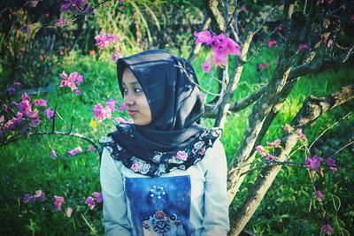 Portrait of woman standing by pink flowering plants