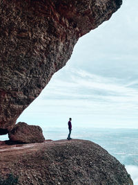 Rear view of man walking on mountain against sky