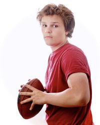 Portrait of boy holding ball against white background